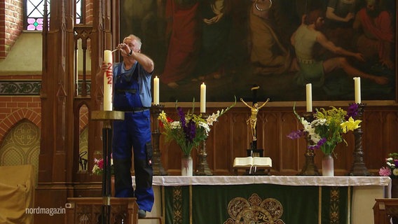 Küster Peter Heidmann entzündet eine Kerze. © Screenshot 