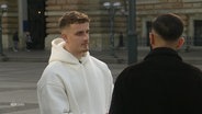 Zwei junge Männer unterhalten sich auf der Straße. © Screenshot 