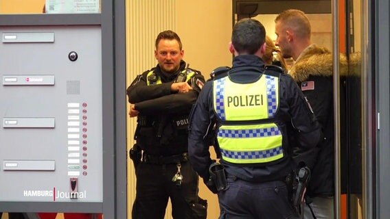 Polizeibeamte stehen in einem Hauseingang. © Screenshot 