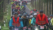 Teilnehmende am Radsport-Event Tour d' Allee fahren über eine Allee. © Screenshot 