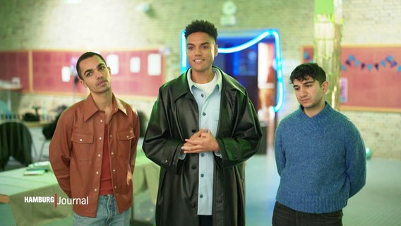 Drei junge Männer stehen vor einem Filmset. © Screenshot 