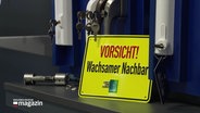 Ein Schild mit der Aufschrift "Vorsicht! Wachsamer Nachbar". © Screenshot 