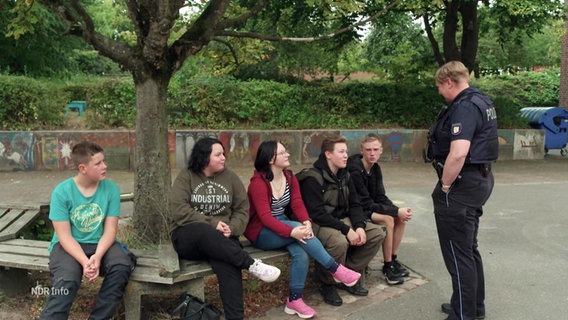 Eine Polizistin unterhält sich mit einer Gruppe Schüler*innen. © Screenshot 