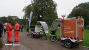 Links im Bild zwei Personen in neon-oranger Arbeitskleidung, rechts im Bild zwei Fahrrad-Mobile der Hamburger Stadtreinigung. © Screenshot 