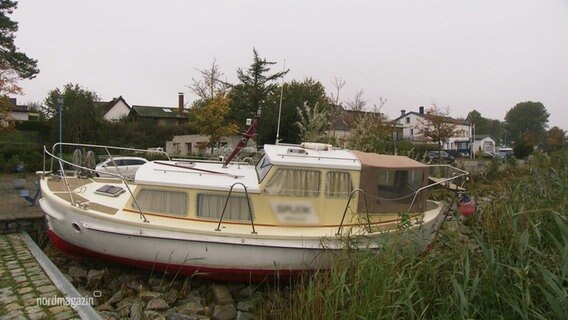 Ein vom Sturm aus dem Wasser gehobenes Motorboot liegt an Land. © Screenshot 