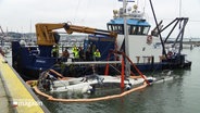 Im Hafen von Schilksee wird ein gesunkenes Sportboot geborgen. © Screenshot 