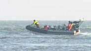 Mehrere Personen sind in einem motorisierten Schlauchboot auf dem Meer. © Screenshot 