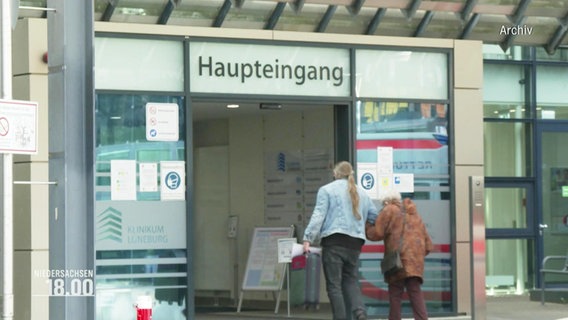Zwei Personen betreten den Haupteingang eines Krankenhauses. © Screenshot 