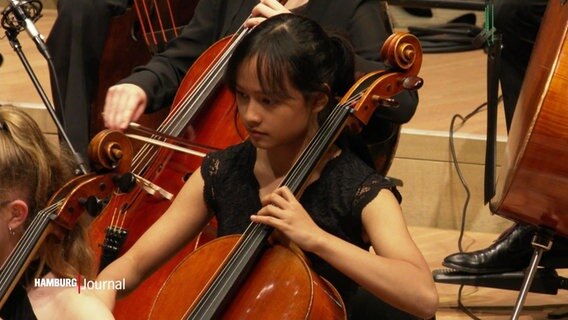 Eine junge Cellistin spielt als Teil eines Orchesters in der Elbphilharmonie. © Screenshot 