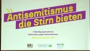 Projektion einer Überschrift bei der Beteiligungskonferenz Aktionsplan gegen Antisemitismus: "Antisemitismus die Stirn bieten". © Screenshot 