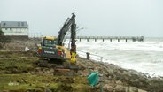 Ein Bagger bei Aufräumarbeiten am Ufer der Ostsee. © Screenshot 