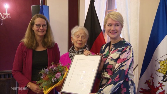 Bettina Martin, Anka Rösler-Kröhnke und Ministerpräsidentin Schwesig mit der Auszeichnung in der Hand. © Screenshot 