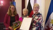 Bettina Martin, Anka Rösler-Kröhnke und Ministerpräsidentin Schwesig mit der Auszeichnung in der Hand. © Screenshot 