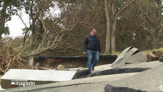 Strandes Bürgermeister Holger Klink (CDU) läuft über den zerstörten Küstenwanderweg. © Screenshot 