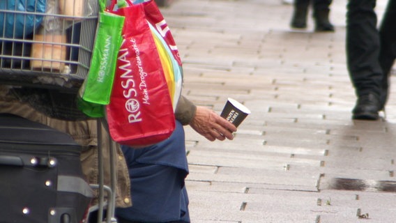 Eine Obdachlose Person hält einen Becher in der Hand. © Screenshot 