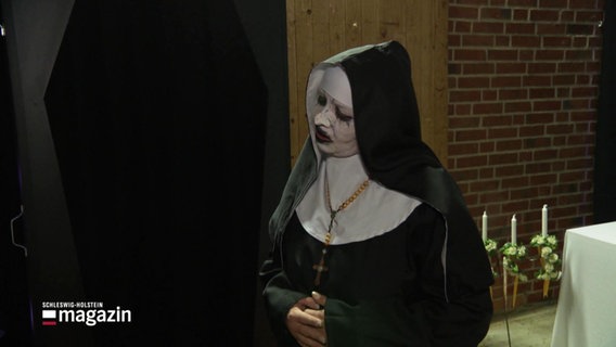 Eine Frau ist als weißgeschminkte Nonne verkleidet. © Screenshot 