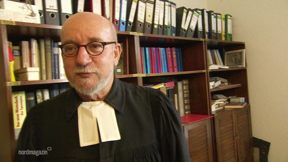 Ein Mensch mit Brille in einer Pastor-Robe. © Screenshot 