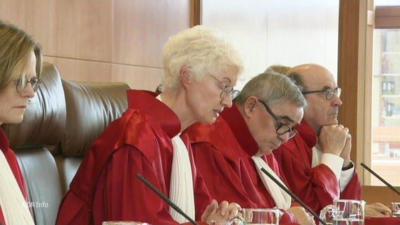 Richter*innen in roten Roben an einem Pult. © Screenshot 