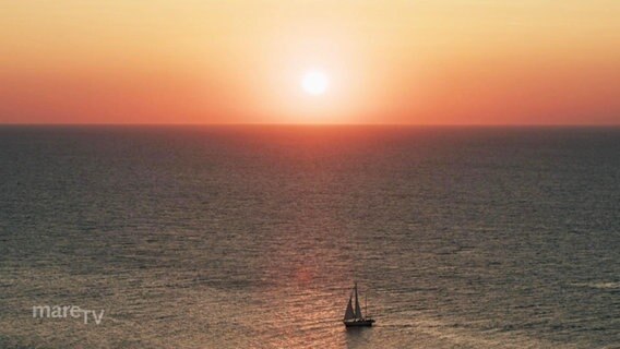 Vogelperspektive: Sonnenuntergang über dem Meer, im Vordergrund ein einzelnes Segelboot. © Screenshot 