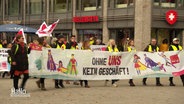 Szene bei dem Streik des Einzelhandels in Osnabrück: Streikende tragen ein langes Banner mit der Aufschrift "Ohne uns kein Geschäft!" © Screenshot 