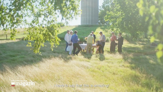 Bild aus dem Eröffnungsfilm der 65. Nordischen Filmtage: Eine Gruppe Erwachsener in einem grünen Garten, sie decken einen Tisch.  Als Untertext zu lesen der Satz: "I have to say that this is amazing!" © Screenshot 