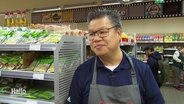 Asia-Supermarkt-Inhaber Li Phung im Gespräch in einem Gang in seinem Lebensmittelgeschäft © Screenshot 