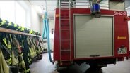 Ein Feuerwehrauto neben Einsatzbekleidung. © Screenshot 