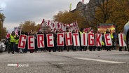 Auf einer Demonstration tragen Menschen Buchstaben-Plakate mit dem Wort "Gerechtigkeit" © Screenshot 