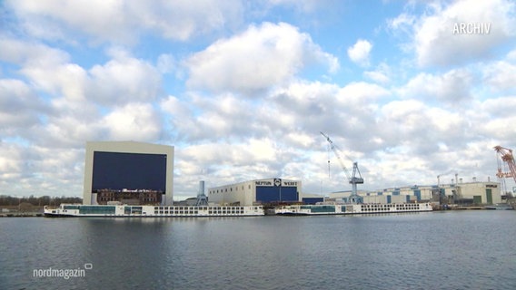 Eine Halle mit der Aufschrift "Neptun Werft". Davor ein Kran. © Screenshot 