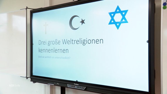 Eine elektronische Tafel im Klassenzimmer mit der Aufschrift: "Drei große Weltreligionen kennnelernen". © Screenshot 