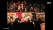 Bilder, wie die Berliner Mauer beklettert wird. © Screenshot 