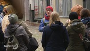Eine kleinere Gruppe von Zuhörenden steht um eine erzählende Frau in einer Fußgängerzone bei einer Stadtführung. © Screenshot 