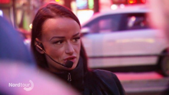 Eine Frau mit Mikrofon-Headset gibt eine Führung auf der Hamburger Reeperbahn. © Screenshot 