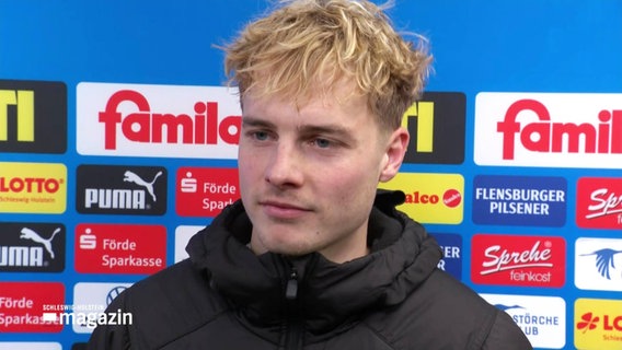 Holstein-Kiel-Spieler Finn Porath vor einer Logowand im Interview © Screenshot 