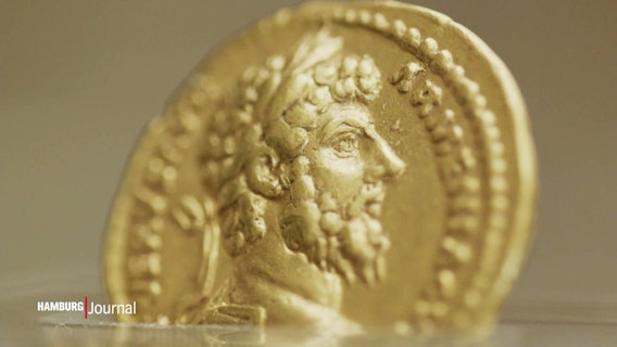 Nahaufnahme einer altertümlichn Goldmünze mit einem darauf abgebildeten Männerkopf © Screenshot 