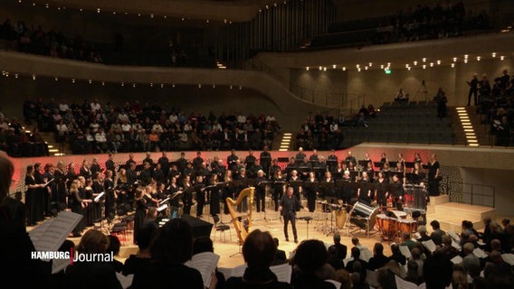 Im großen Saal der Hamburger Elbphilharmonie treten bei einem Konzert viele hundert Menschen als großes Vokalensemble auf. © Screenshot 