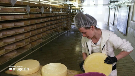 Eine Frau bewegt einen Laib Käse. © Screenshot 