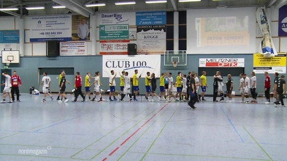 In einer Halle geben sich zwei Handball-Mannschaften nach einem Spiel die Hand. © Screenshot 