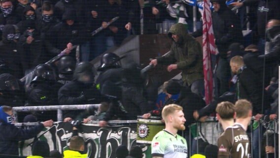 Polizisten und Fans geraten aneinander, vorne stehen Spieler auf dem Feld © Screenshot 