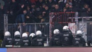 Mehrere Polizisten sind bei einem Einsatz in einem Fußballstadion tätig. © Screenshot 
