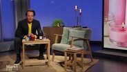 Im Studio von "Markt": Zwei Sessel und ein kleiner Tisch mit einigen Duftkerzen und Duftstäbchen, in einem Sessel sitzt der Moderator Jo Hiller. © Screenshot 