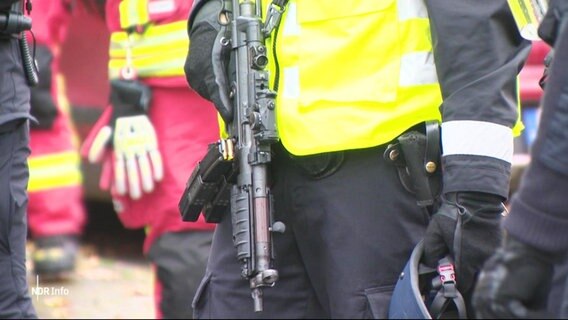 Ein Polizist hält eine Maschinenpistole. © Screenshot 