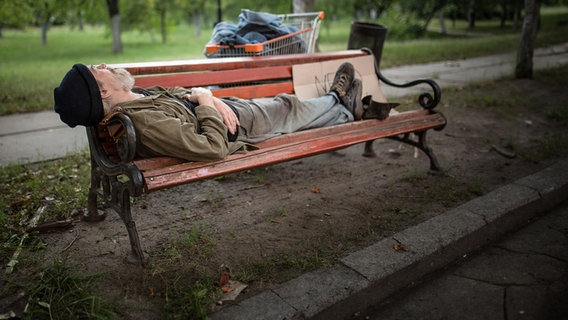 Ein Obdachloser liegt auf einer Parkbank. Wohnungsnot und Obdachlosigkeit: Was läuft schief? (extra 3 vom 15.11.2023 im NDR Fernsehen) © NDR 