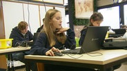 Schülerinnen vor Laptops in einem Klassenraum. © Screenshot 