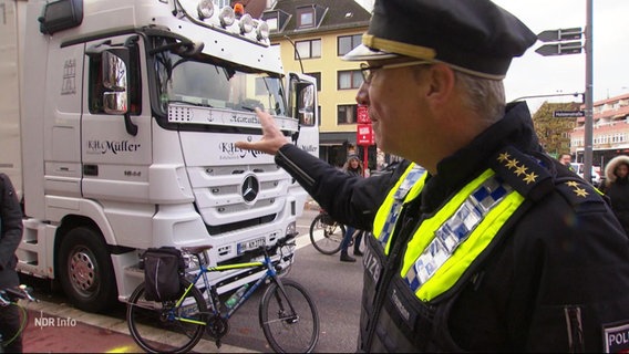 Ein Polizist zeigt auf einen Lkw. © Screenshot 