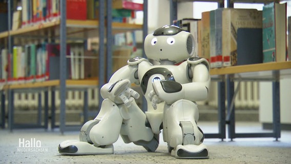 Ein kleiner Roboter siitzt in der Stadtbücherei Emden auf dem Fußboden. © Screenshot 