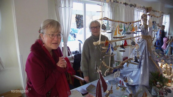 Zwei Frauen mit einem Stand mit Glasdekorationen am Kunsthandwerkermarkt in der Ostseemühle Langenhanshagen. © Screenshot 