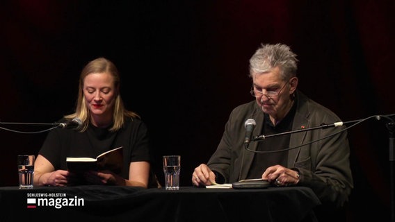 Marie Kienecker und Norbert Aust sitzen auf einer Bühne und lesen aus Büchern © Screenshot 