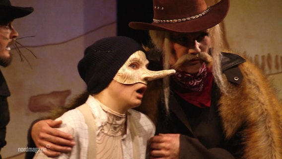 Zwei Schauspieler stellen einen Jungen mit langer Nase und einen älteren Mann mit Bart und Hut dar. © Screenshot 
