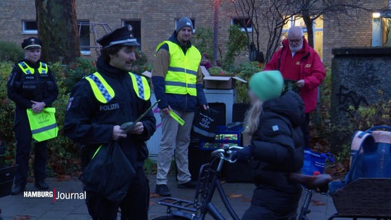Ein Polizeibeamter unterhält sich mit einer Schülerin auf einem Fahrrad. © Screenshot 